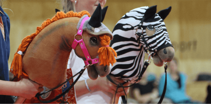 Dva Hobby Horses so zapletenými hrivami, jeden hnedý s oranžovou priadzou a druhý so zebrovým vzorom