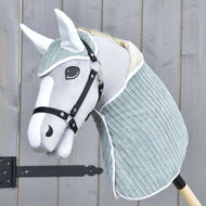 Set Manchester Little Green od Hobby Horse LarDen so sivo-bielym Hobby Horse s mäkkou látkovou hlavou, čiernou uzdečkou, čabrakou a svetlým modrozeleným krytom krku na drevenej tyči, zobrazený pred dreveným plotom.