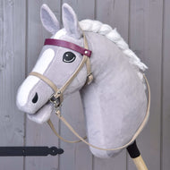 Hobby Horse LarDen so sivým Hobby Horse s bielou hrivou, čiernym okom a koženkovým setom Bordeaux – uzdečka, opraty a martingal –, doplneným o fialovú čelenku a tvár v kreslenom štýle. Stojí vzpriamene pred dreveným pozadím.