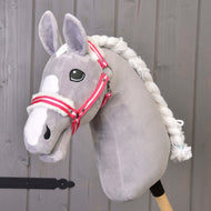 Hobby Horse LarDen "Ohlávka s červeným prúžkom a barančekom" je sivý plyšový Hobby Horse s bielou hrivou a ohlávkou s červeným prúžkom na drevenej tyči, zobrazený pred sivou drevenou stenou.