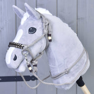 Povrazový set Splendid od Hobby Horse LarDen na sivom plyšovom Hobby Horse s bielou hrivou, čiernymi očami a povrazovou uzdečkou s opratami, pred sivou drevenou stenou.