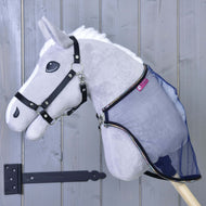 Sivý plyšový Hobby Horse LarDen s čiernou uzdečkou a pripevnenou dekou proti hmyzu LarDen, zobrazený pred svetlosivými drevenými dverami s čiernym pántom.