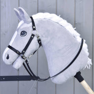 Čierne opraty z koženky od Hobby Horse LarDen na sivom plyšovom Hobby Horse s bielou hrivou, bezzubadlovou uzdečkou a kvalitnými čiernymi opratami z koženky, na drevenej tyči pred sivým dreveným panelovým pozadím.