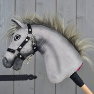 Hobby Horse Prestige s čiernou ohlávkou, veľkosť XS od Hobby Horse LarDen, je sivá plyšová hlava Hobby Horse inšpirovaná eleganciou športového anglického teplokrvníka. Má výraznú vyšívanú tvár, divokú hrivu a pevnú čiernu ohlávku, nasadenú na drevenej tyči. Na drevenom pozadí, ideálna pre nápadité dobrodružstvá pri parkúrovom skákaní.
