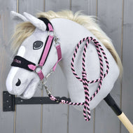 Set LarDen Exclusive Pink od Hobby Horse LarDen, sivý plyšový Hobby Horse s krémovou hrivou, ružovo-čiernou uzdečkou, ladiacim fleecovým nánosníkom a vodidlom na čiernej tyči, na drevenom pozadí.