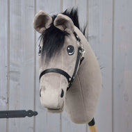 Hobby Horse Thor s čiernou ohlávkou od Hobby Horse LarDen, s mäkkou sivou hlavou, čiernou hrivou a postrojom na drevenej tyči, na pozadí svetlých drevených panelov.