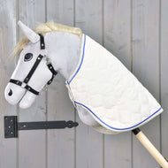 Hobby Horse LarDen so sivou plyšovou hlavou, čiernou uzdečkou a dekou Cream Pearl s modrým lemovaním na drevenej tyči, zobrazený pred sivou drevenou stenou.