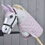 Hobby Horse LarDen Set Sweetest Heart obsahuje plyšový Hobby Horse so svetlosivou tvárou, čiernou uzdečkou, svetlou hrivou, ružovými ušami s čabrakou a prešívanou ružovou dekou, zobrazený na drevenom pozadí.