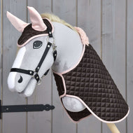 Hobby Horse LarDen Set Thermo Sweety s plyšovým Hobby Horse s uzdečkou, oblečeným do prešívanej hnedo-ružovej deky a ladiacej čabraky, vystavený na drevenom pozadí.