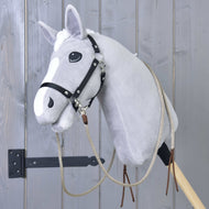 Sivý plyšový Hobby Horse od Hobby Horse LarDen s Westernovými oprátami Dallas delenými a čiernou uzdečkou, nasadený na drevenej tyči pred sivou drevenou stenou.