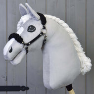 Čierna ohlávka z koženky s čiernym barančekom od Hobby Horse LarDen na plyšovom svetlosivom koni s čiernou koženkovou ohlávkou a veľkými vyšívanými očami, pred sivým dreveným pozadím.