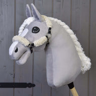 Plyšový sivý Hobby Horse od Hobby Horse LarDen s čiernou ohlávkou s kompletným barančekom a detailmi z koženky, na drevenej tyči pred pozadím z drevených dosiek.