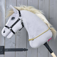 Sivý Hobby Horse LarDen s čiernou uzdečkou, zlatou hrivou a ručne vyrobeným Nákrčníkom Nature visí na drevenej tyči pred sivou stenou. Okolo krku má omotané žlté polypropylénové lano.