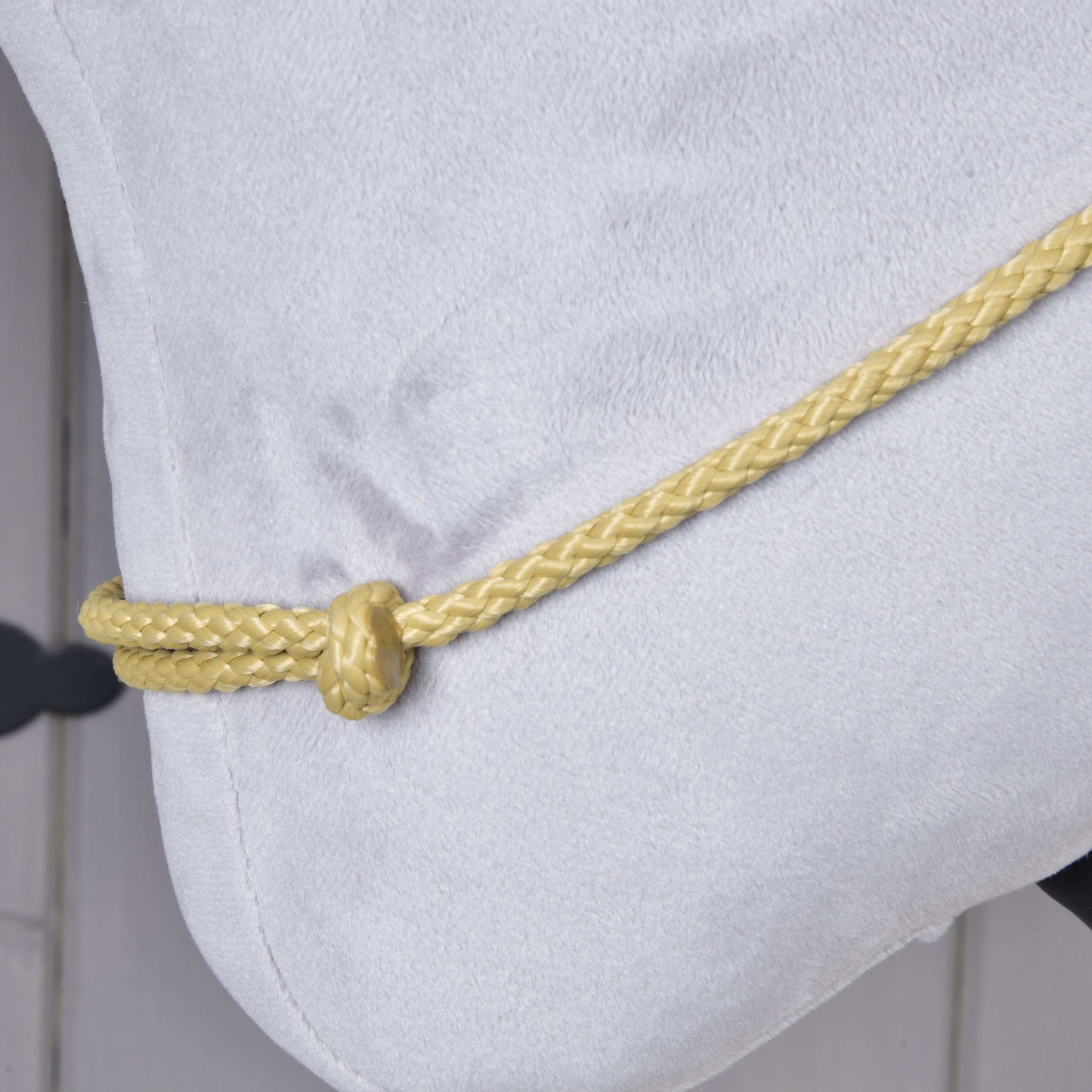 Detail Nákrčníka Nature od Hobby Horse LarDen, zobrazujúci mäkkú svetlosivú látku so žltou ručne pletenou šnúrou uviazanou do jednoduchého uzla pozdĺž okraja.