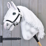 Hobby Horse Elektra s černou ohlávkou od Hobby Horse LarDen s ručně malovanou bílou hlavou, černou ohlávkou a dlouhou bílou přízovou hřívou, nasazený na dřevěné tyči před světle šedou dřevěnou stěnou.