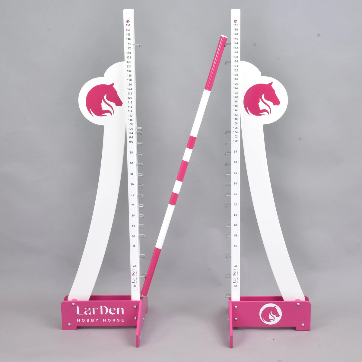 LarDen skok mohutnosti od Hobby Horse LarDen, dve biele a ružové nastaviteľné stojky s logami konskej hlavy držia vodorovne pruhovanú tyč, na jednofarebnom sivom pozadí.