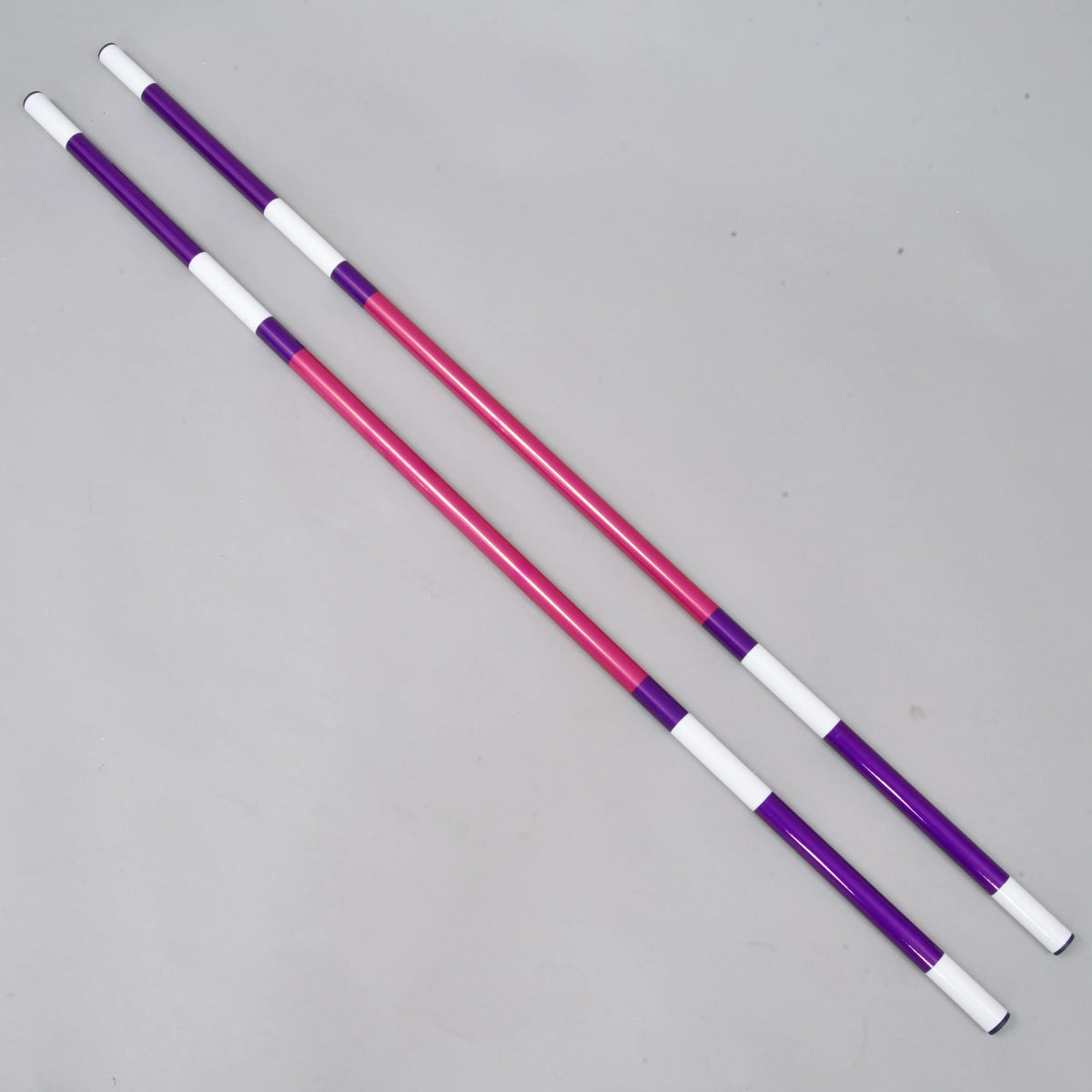 Bariérka ružovo-fialová, 2 ks od Hobby Horse LarDen, dve ľahké tyče s priemerom 32 mm so striedajúcimi sa fialovými, ružovými a bielymi časťami, ležiace rovnobežne na jednofarebnom svetlosivom pozadí. Poťahované PVC zaisťuje ľahkú manipuláciu.