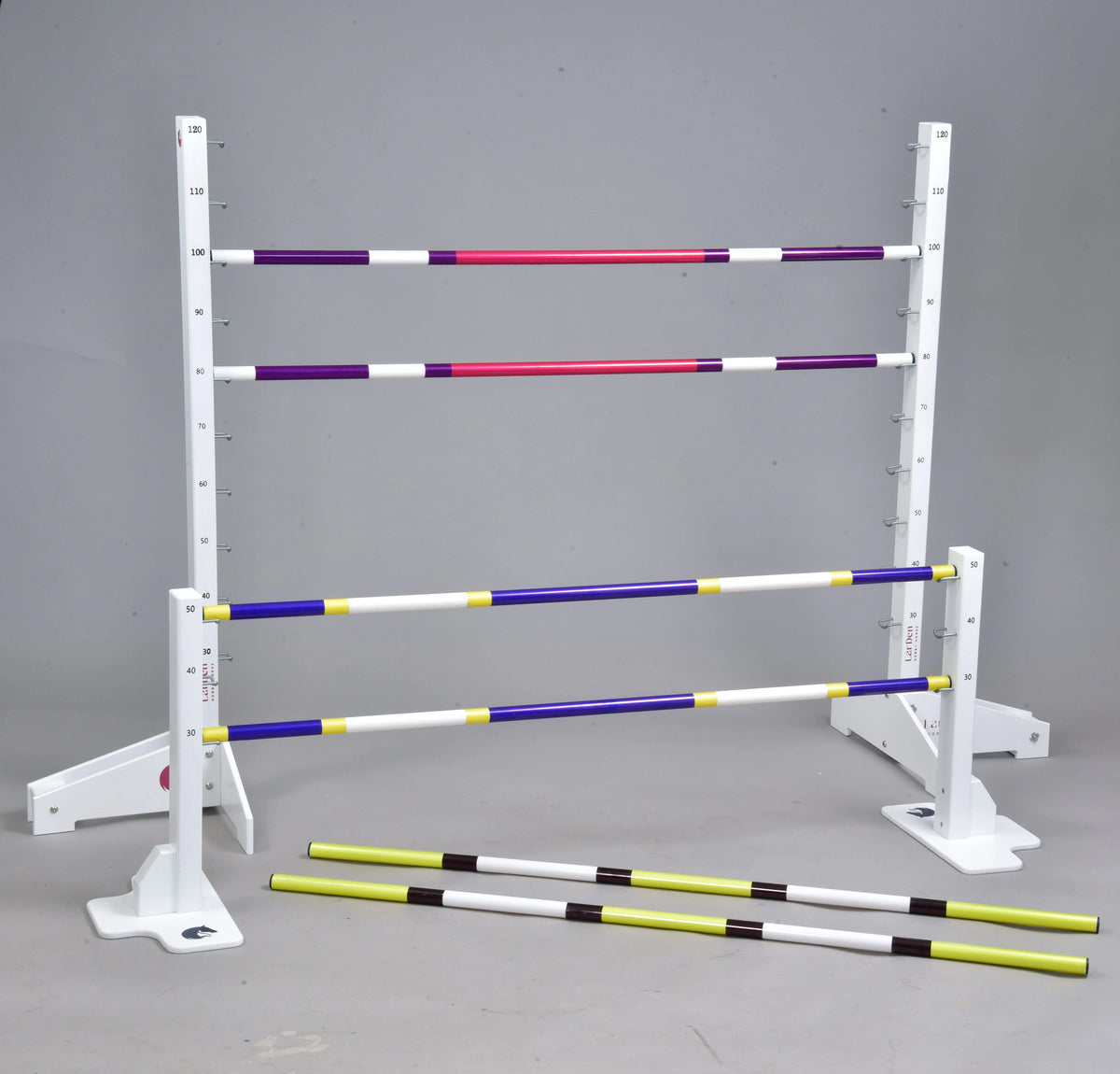 Set prekážok pre Hobby Horsing od Hobby Horse LarDen zahŕňa biele nastaviteľné prekážky a farebné tyče, usporiadané v rôznych výškach alebo na zemi, ideálne na tréning v jazdeckom štýle, cavaletti alebo dog agility.