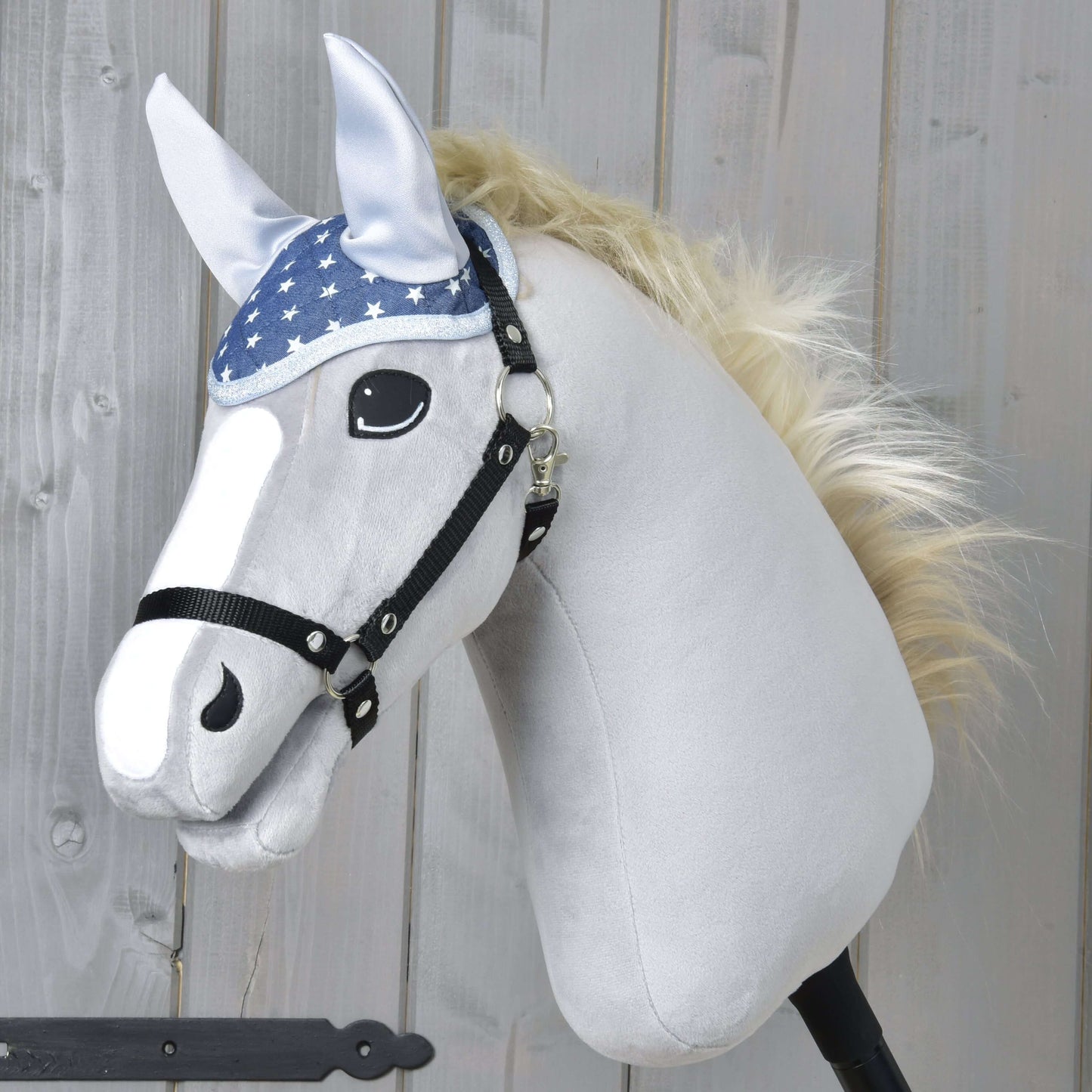 Čabraka Star od Hobby Horse LarDen na plyšovom koníkovi na tyči s bielou tvárou, čiernou uzdečkou, modrou čabrakou s hviezdami na ochranu proti hmyzu, svetlou hrivou a kreslenými očami, zobrazenom na drevenom pozadí.