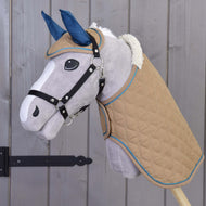 Set Almond Star od Hobby Horse LarDen s plyšovým Hobby Horse, béžovou prešívanou dekou, modrou čabrakou, bielou hrivou a čiernou uzdečkou na drevenej tyči, zobrazený pred sivou drevenou stenou.