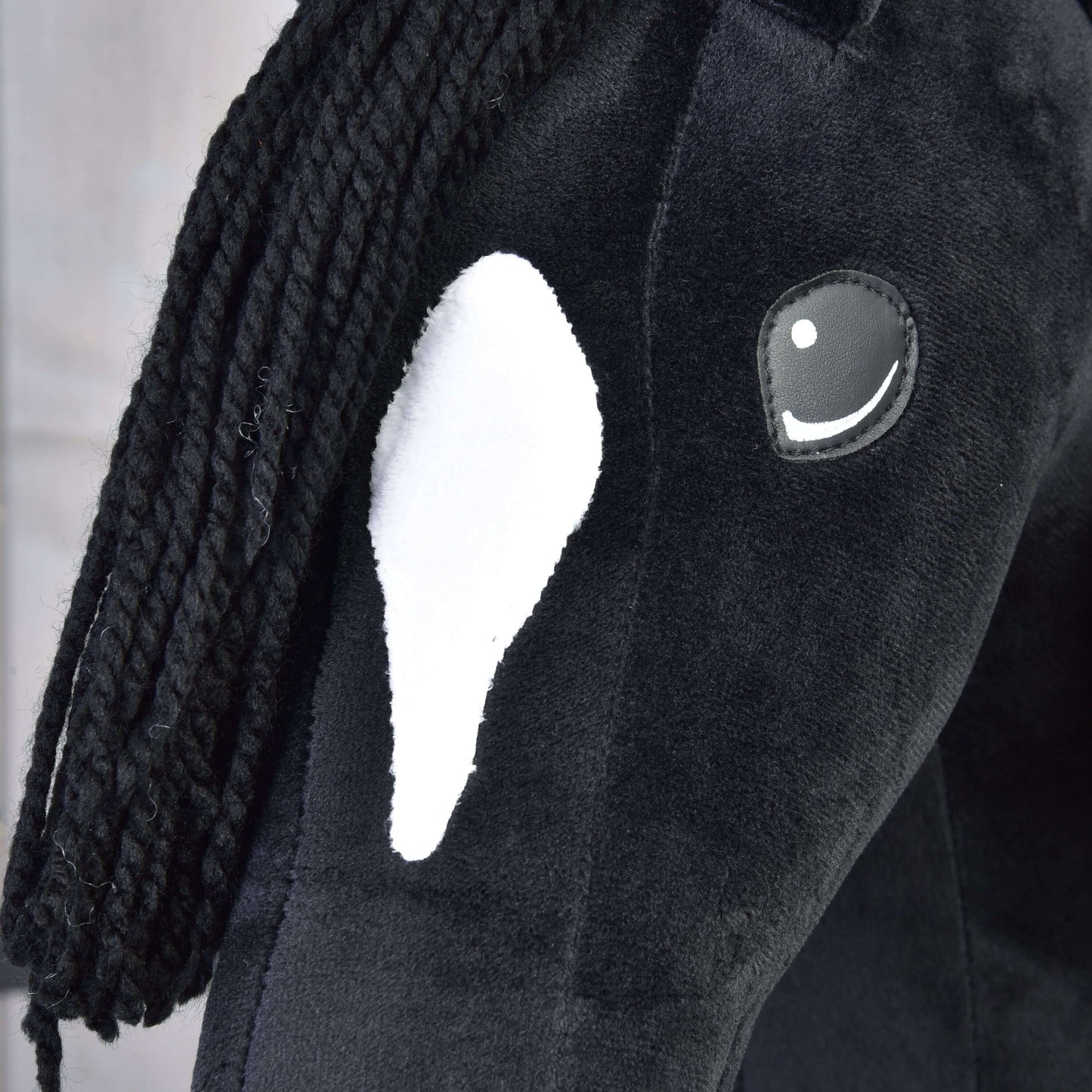 Detail Hobby Horse Cloony s čiernou ohlávkou od Hobby Horse LarDen, čierny plyšový Hobby Horse s bielou škvrnou na hlave, čiernou priadzovou hrivou a vyšívaným okom s bielym odleskom.