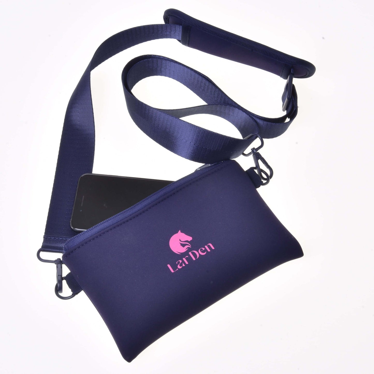 Crossbody od Hobby Horse LarDen v tmavomodrej farbe z neoprénu s uzatváraním na zips, dlhým nastaviteľným popruhom, čiastočne viditeľným smartfónom vnútri a ružovým logom koňa s nápisom „LarDen“ na prednej strane.