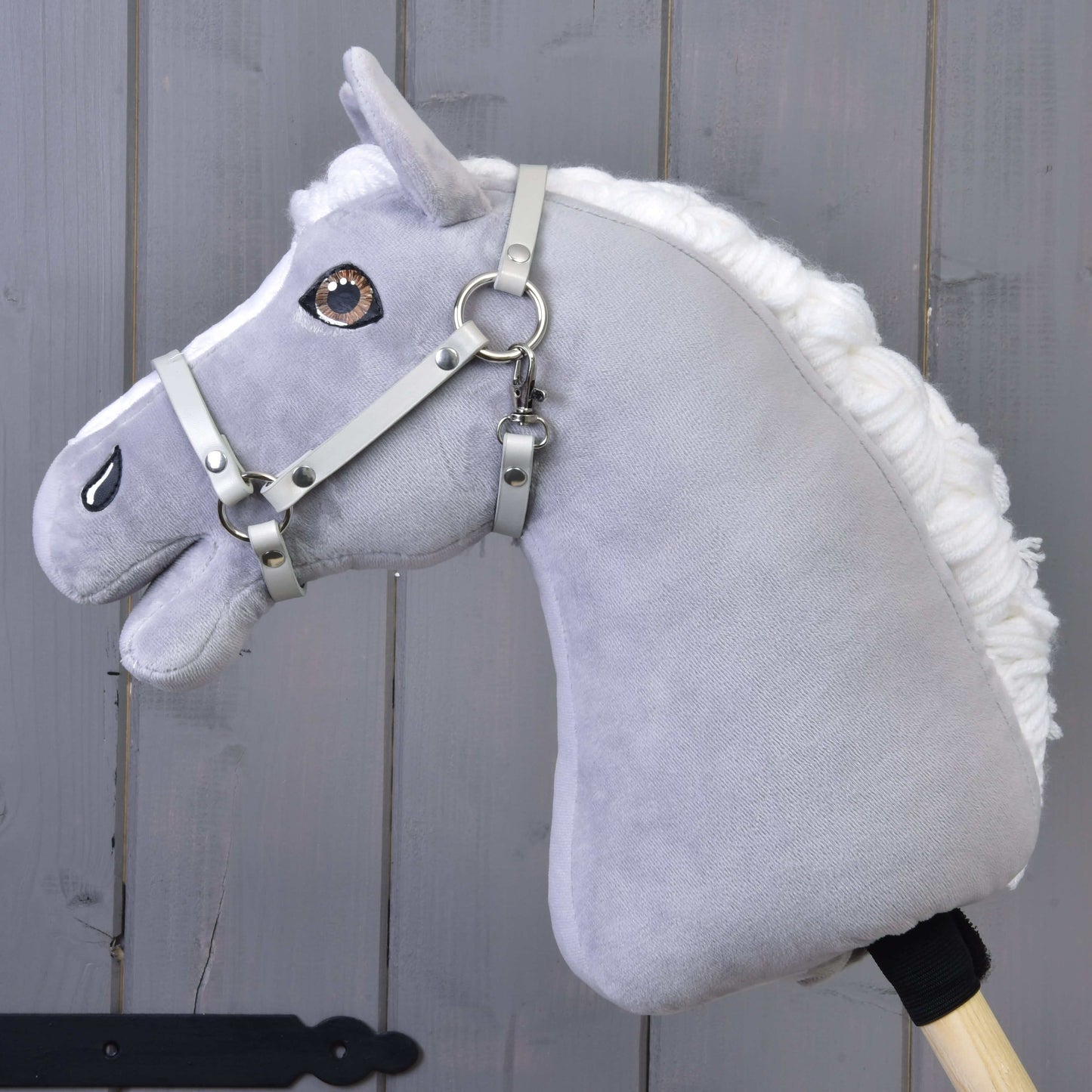 Ohlávka - světle šedá koženka (vel. S) od Hobby Horse LarDen na šedém plyšovém koni s bílou hřívou, hnědýma očima a dřevěnou tyčí, zobrazeném na šedém dřevěném pozadí.