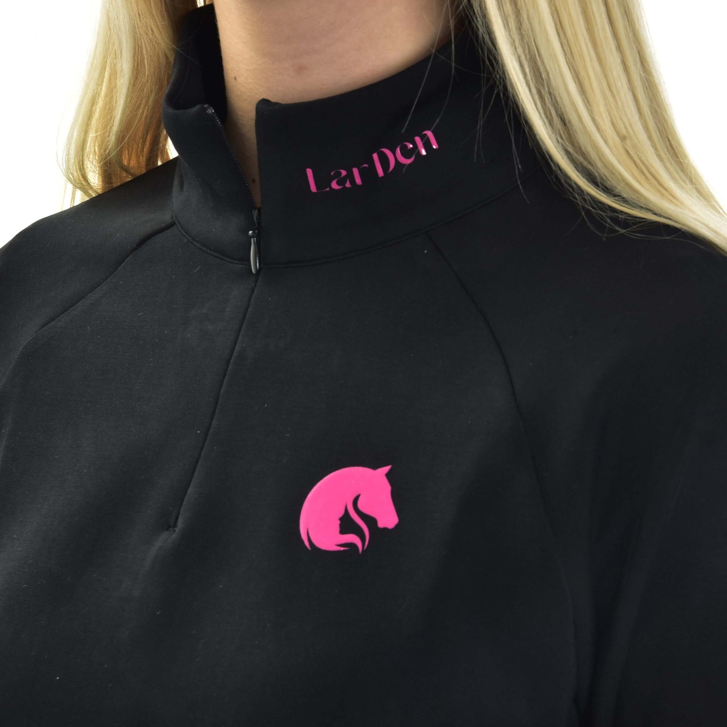 Osoba s dlhými blond vlasmi má na sebe mikinu LarDen od Hobby Horse LarDen – čierny top na zips s ružovým logom konskej hlavy na hrudi a nápisom LarDen v ružovej farbe pri golieri.