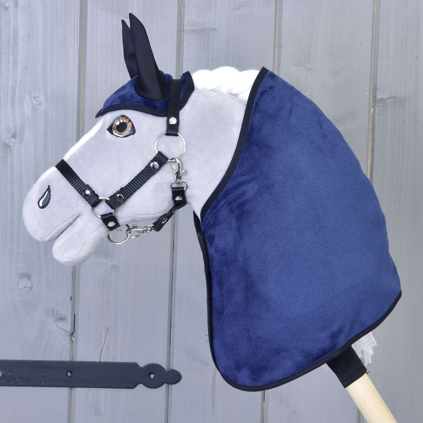 Set Dark Blue (čabraka + deka) od Hobby Horse LarDen s hlavou plyšového Hobby Horse s bílou hřívou, černou uzdečkou, modrou čabrakou a dekou, upevněnou na dřevěné tyči a zobrazenou na pozadí světlého dřevěného plotu.