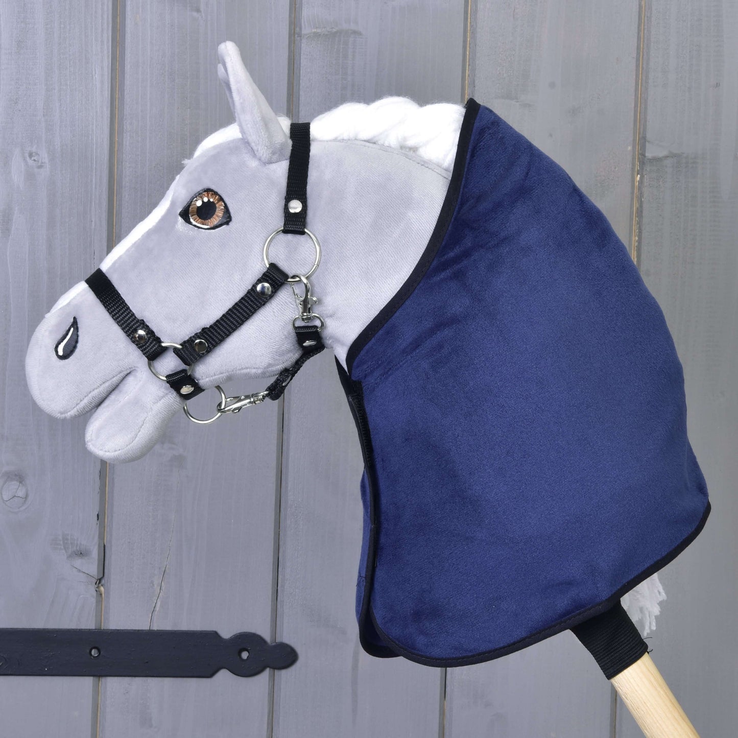 Set Dark Blue (čabraka + deka) od Hobby Horse LarDen na šedém plyšovém koni s bílou hřívou, černou uzdou, tmavě modrou výbavou a dřevěnou tyčí, ideální pro jakékoli Hobby Horsing dobrodružství.