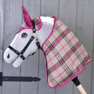 Set Cube Pink od Hobby Horse LarDen se plyšovým Hobby Horse se šedým obličejem, černou uzdečkou a kostkovanou dekou v béžové, růžové a černé barvě, zobrazený před dřevěnou stěnou.