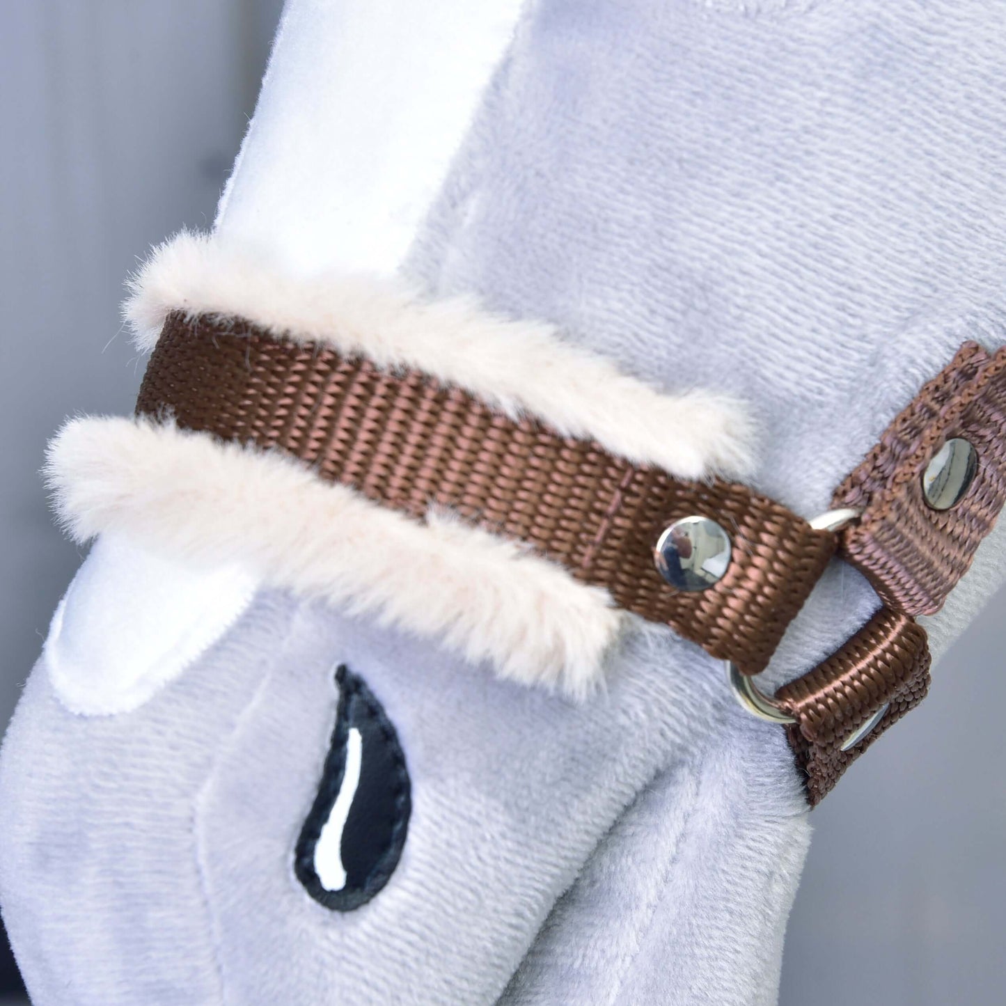 Detailný záber na Ohlávku hnedú s barančekom od Hobby Horse LarDen, doplnok pre svetlosivého plyšového Hobby Horse s hnedou ohlávkou, bielym lemom z umelej kožušiny, kovovými cvočkami a prešitým čiernym detailom v tvare kvapky.