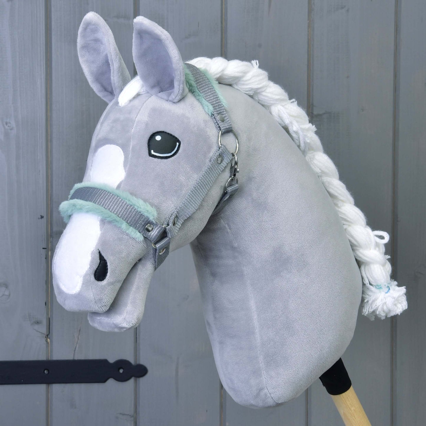 Hobby Horse LarDen Ohlávka sivá s mint barančekom – plyšový sivý doplnok pre Hobby Horse s bielou hrivou a znakmi na hlave – na sivom drevenom pozadí.