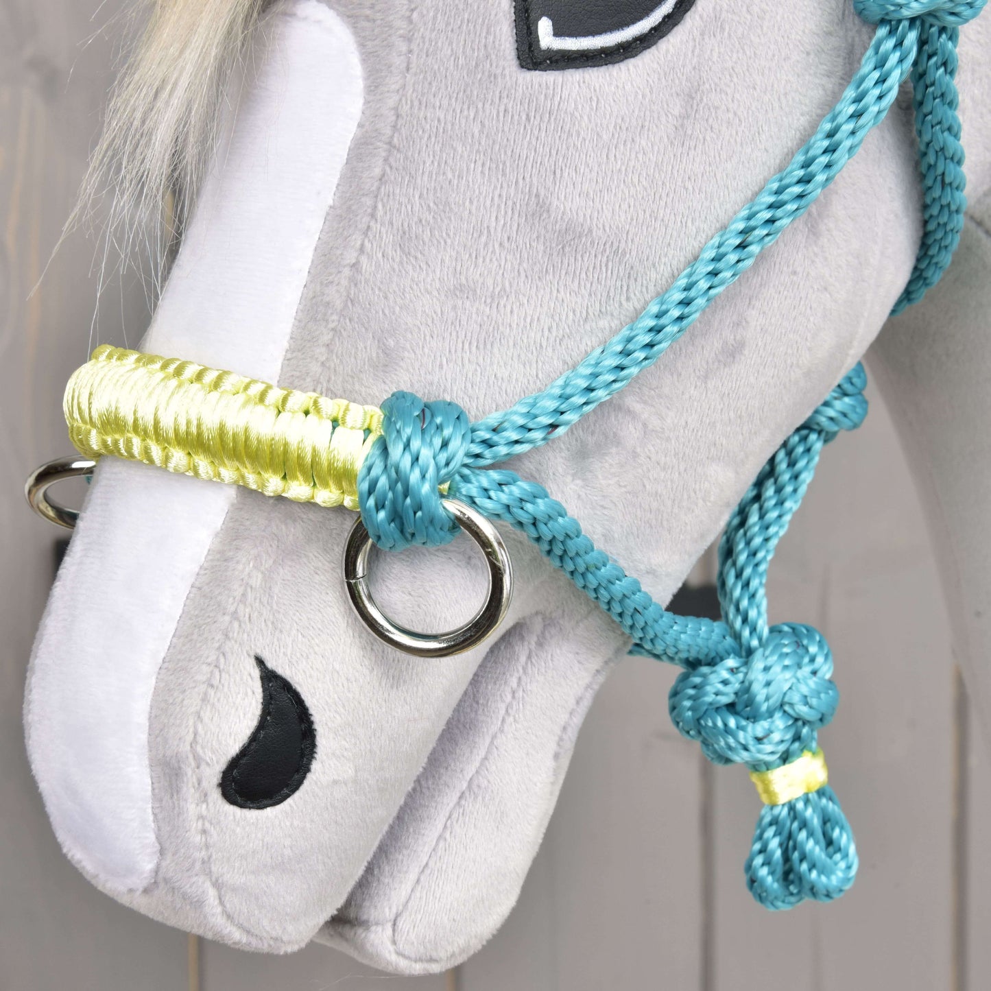 Detail sivého plyšového Hobby Horse od Hobby Horse LarDen s Parelka Tyrkys a uzdečkou, čierne vyšívanými očami a nozdrami a hrivou z bielej priadze.