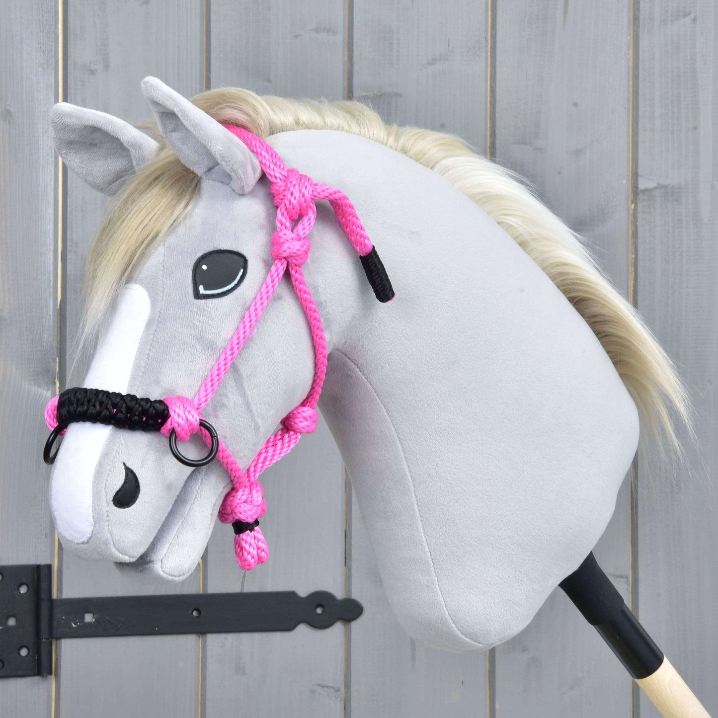 Hobby Horse LarDen Parelka Pink na plyšovom Hobby Horse so svetlosivou látkou, bielou hrivou a bielym pruhom na tvári, zobrazená na drevenom pozadí.
