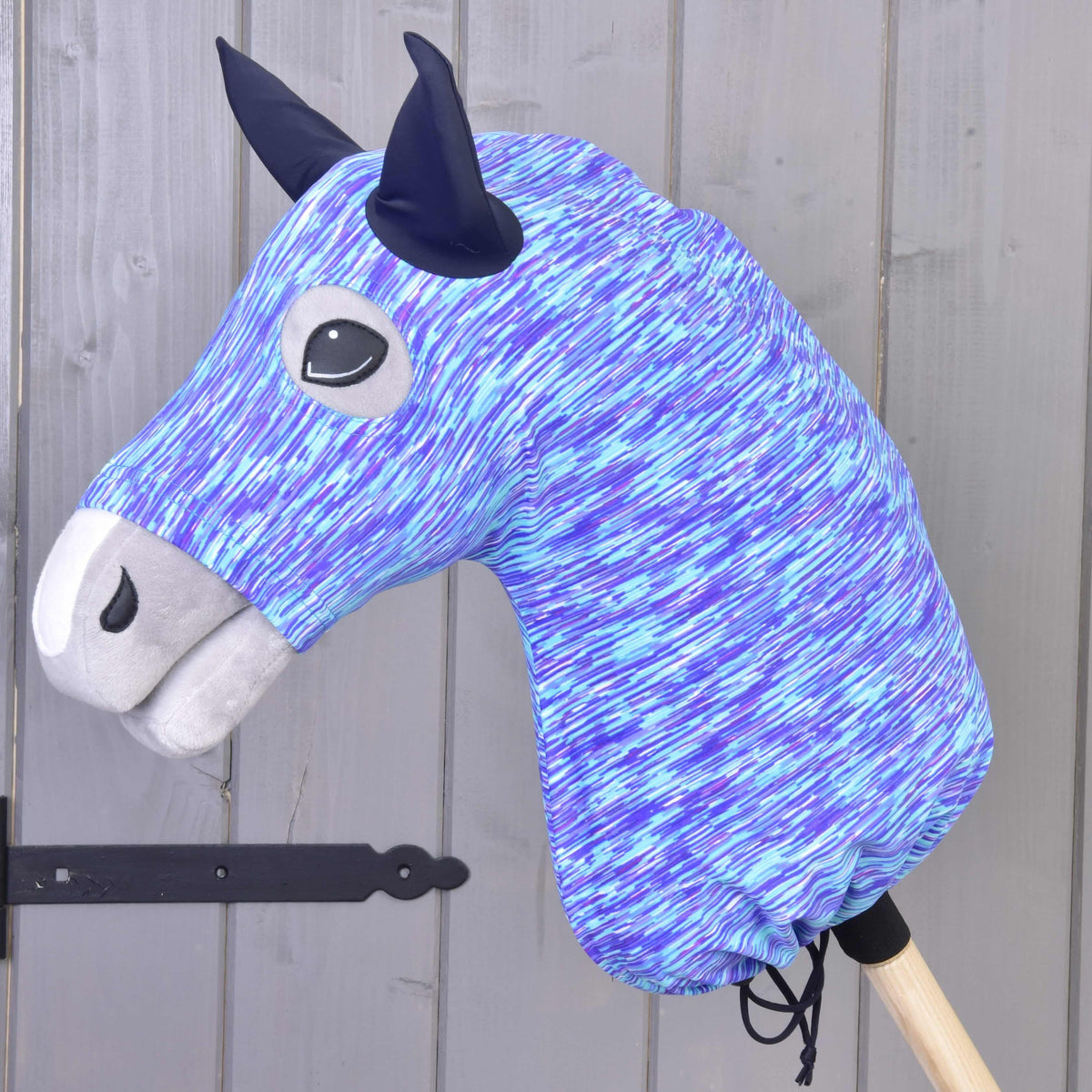Hobby Horse ochranný oblek Sea (Lycra) od Hobby Horse LarDen je modrobiely škvrnitý prateľný poťah s čiernymi ušami a sivým ňufákom, s priateľskou tvárou a zobrazený na pozadí dreveného obkladu.