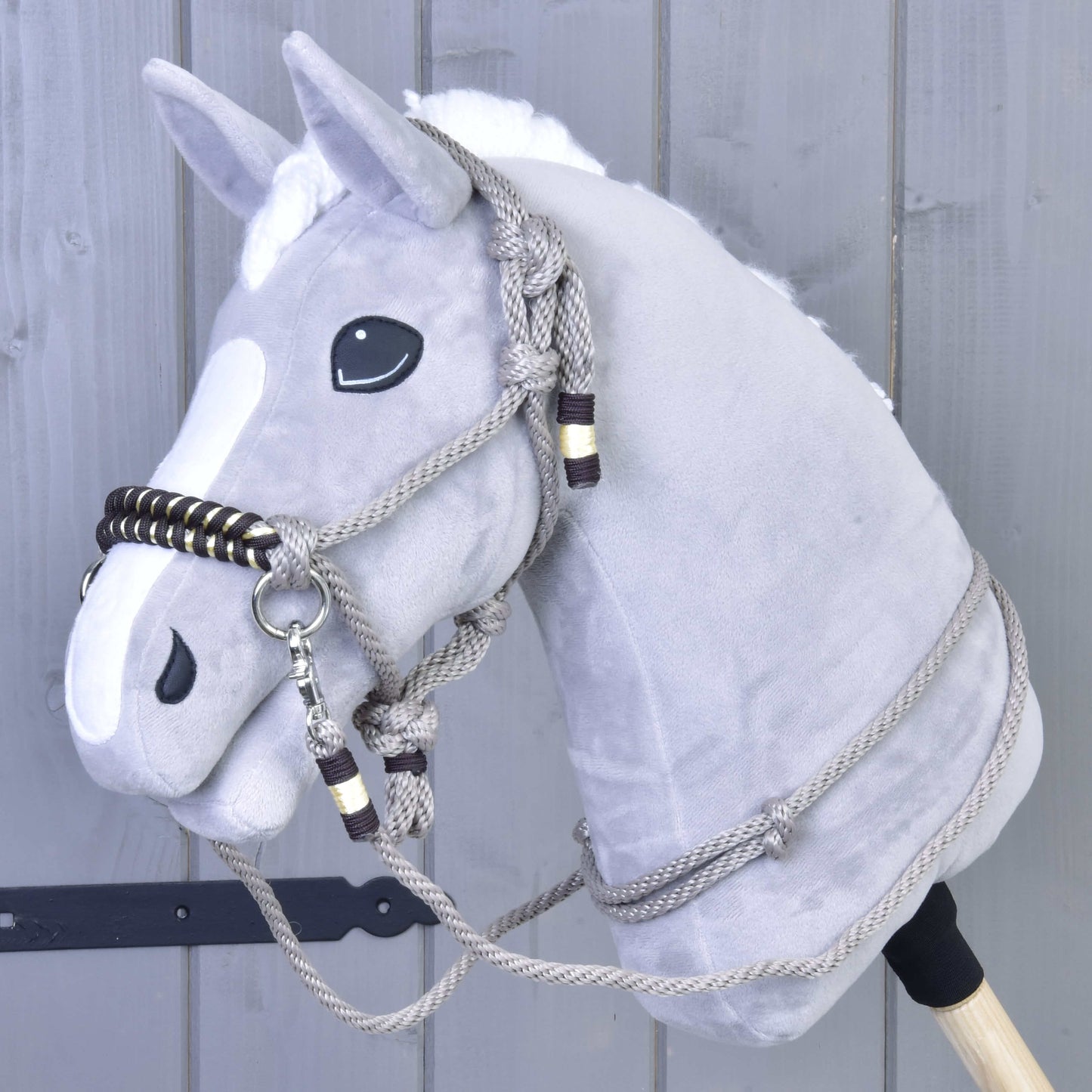 Povrazový set Splendid od Hobby Horse LarDen na sivom plyšovom Hobby Horse s bielou hrivou, čiernymi očami a povrazovou uzdečkou s opratami, pred sivou drevenou stenou.