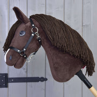 Hobby Horse Chianti s černou ohlávkou od Hobby Horse LarDen, s hnědým tělem, přízovou hřívou a bílým detailem na nose, je zobrazený na dřevěné tyči před světle šedou dřevěnou stěnou.