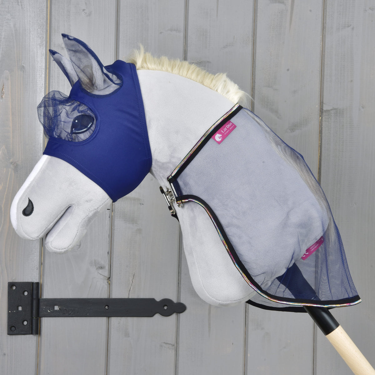 Hobby Horse LarDen Set Fly Combo s plyšovým Hobby Horse, modrou maskou proti hmyzu a sieťovanou dekou proti hmyzu na drevenej tyči, na pozadí sivej drevenej steny, pripravený na tvoje ďalšie dobrodružstvo.