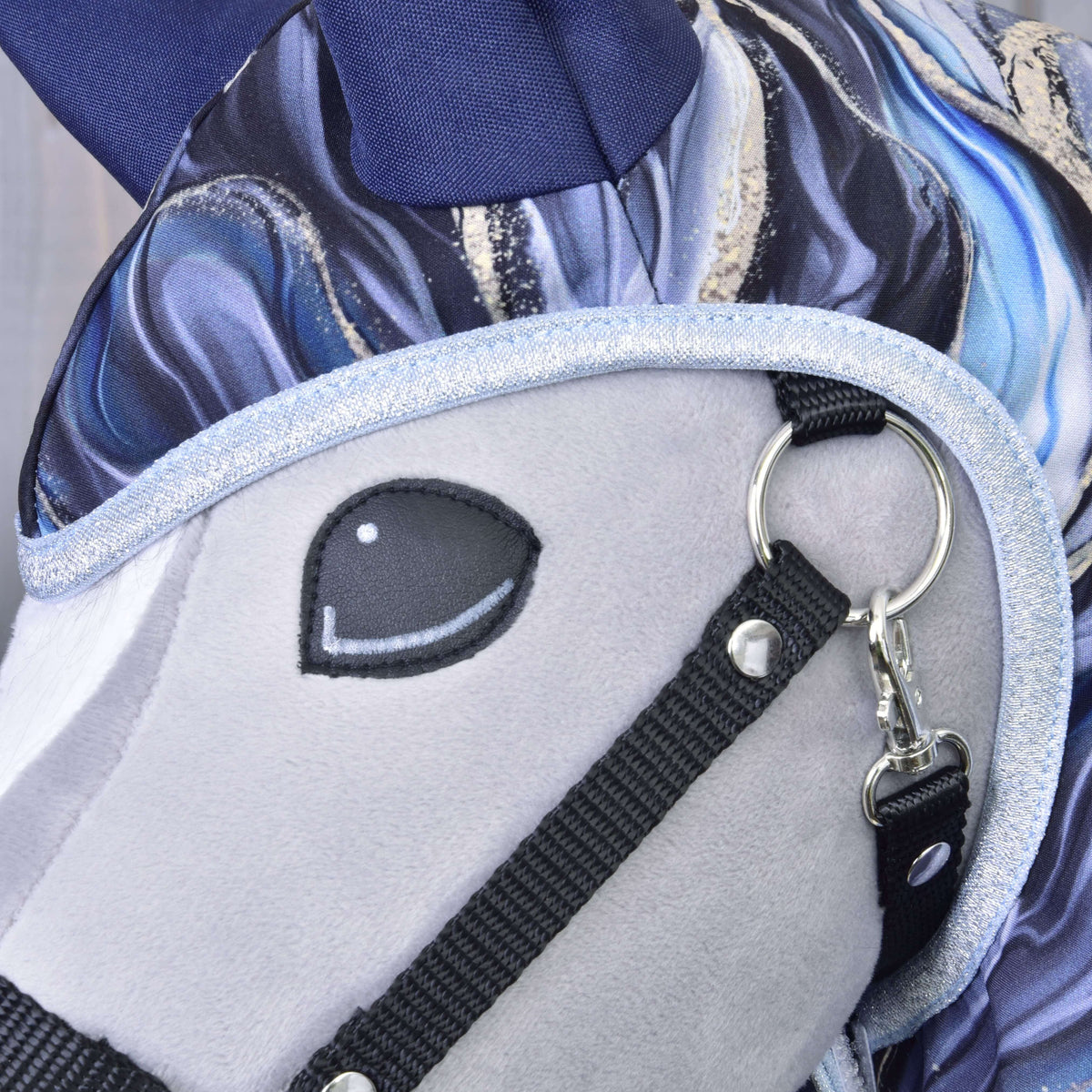 Detail plyšovej hlavy Pláštenka Galaxy Cobalt od Hobby Horse LarDen, so svetlosivou tvárou, vyšívaným čiernym okom, lesklým strieborným lemom uzdečky a modrobielo vzorovanou hrivou – skvelé na zladenie s tvojimi obľúbenými doplnkami pre Hobby Horse.