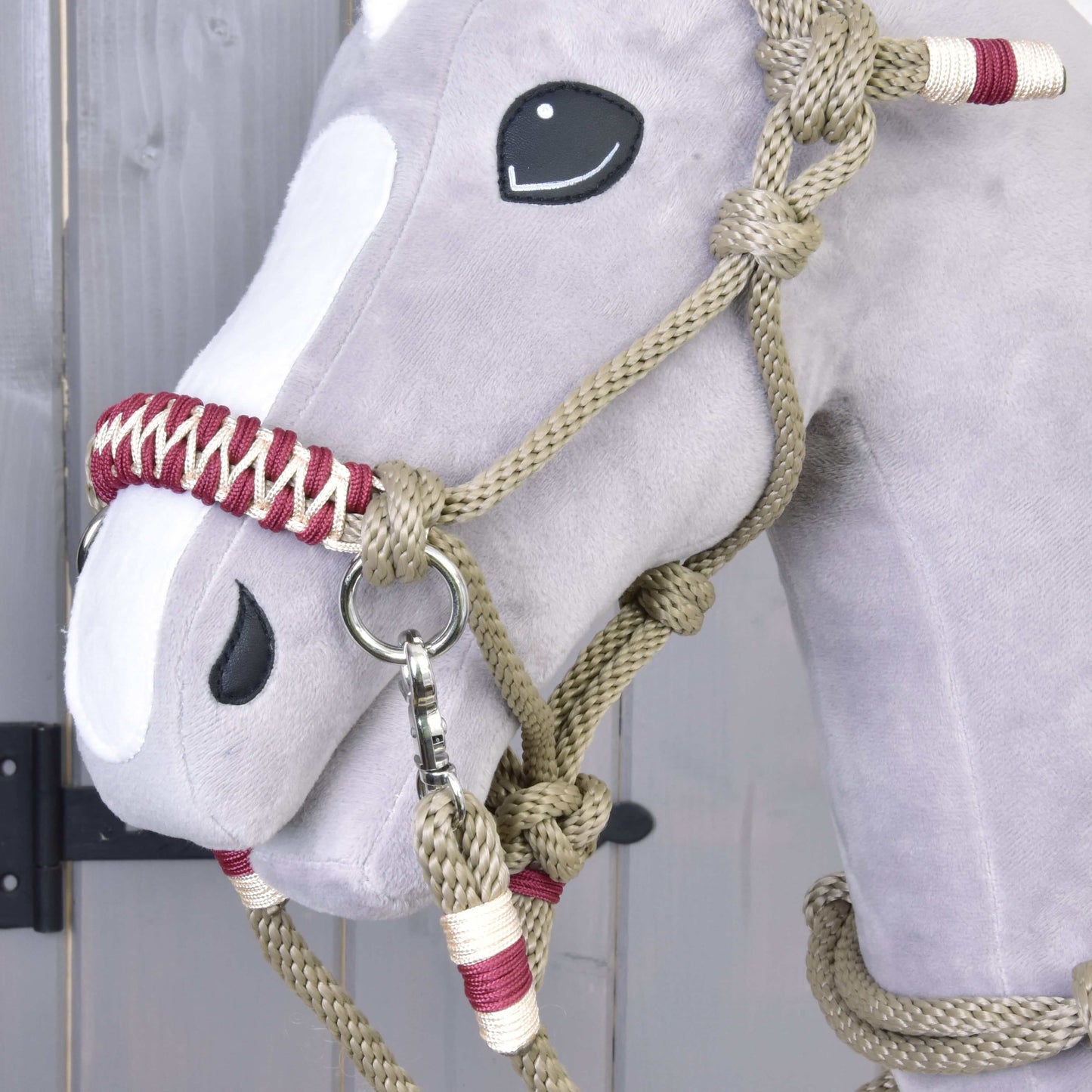 Detail hlavy Hobby Horse LarDen s povrazovým setom Eleganza – mäkký sivý Hobby Horse s čiernymi gombíkovými očami, bielymi plstenými časťami a béžovo-červenou ohlávkou na drevenom pozadí.