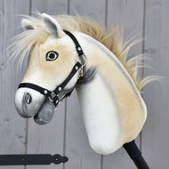 Hobby Horse Honey Pearl s čiernou ohlávkou - veľkosť S od Hobby Horse LarDen, detail béžovobieleho plyšového koňa inšpirovaného oldenburským plemenom s čiernou ohlávkou, huňatou hrivou a priateľskou detailne spracovanou tvárou, na pozadí drevených panelov.