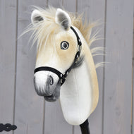 Hobby Horse Honey Pearl s čiernou ohlávkou - veľkosť S od Hobby Horse LarDen, plyšový Hobby Horse v štýle oldenburského koňa s béžovou hrivou, sivým ňufákom a čiernou ohlávkou, nasadený na tyči pred sivou drevenou stenou.