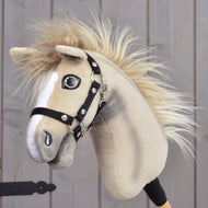 Hobby Horse Ivory Dream s čiernou ohlávkou – veľkosť XS od Hobby Horse LarDen, držaný osobou, so svetlobéžovou srsťou, bielymi znakmi na hlave, huňatou hrivou a čiernou ohlávkou na drevenom pozadí.
