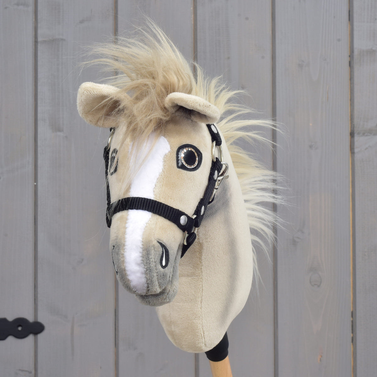 Hobby Horse Ivory Dream s čiernou ohlávkou – veľkosť XS od Hobby Horse LarDen s béžovo-bielym plyšovým prevedením, gombíkovými očami a huňatou hrivou na svetlom drevenom pozadí.