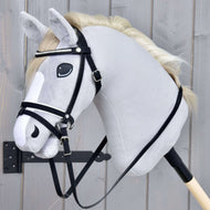 Kompletní uzdečka De Luxe se 2 čelenkami od Hobby Horse LarDen na realistickém šedém Hobby Horse na tyči s bílou hřívou a kombinovaným nánosníkem, nasazeném na dřevěné tyči před šedým dřevěným pozadím.
