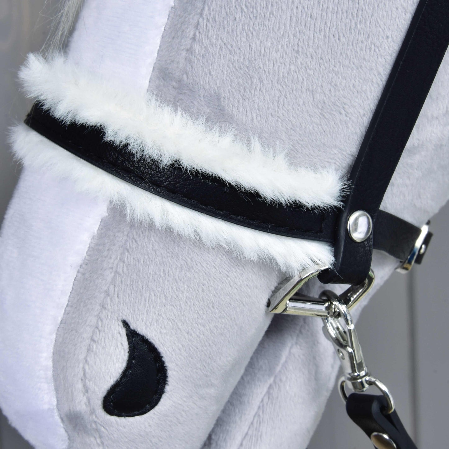 Detail Kompletnej uzdečky s barančekom čiernej od Hobby Horse LarDen: mäkká svetlosivá plyšová konská hlava s koženkovou uzdečkou, bielym lemovaním z umelej kožušiny, čiernym polmesiacovým detailom nozdry a jemne štruktúrovaným povrchom.