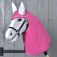 Pláštenka LarDen od Hobby Horse LarDen na sivej hračke Hobby Horse s čiernou uzdečkou a ružovou kapucňou na ochranu pred nepriaznivým počasím, zobrazená pred drevenou stenou.