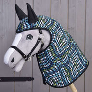 Plyšový Hobby Horse LarDen s čiernou ohlávkou má na sebe Pláštenku Lara s kapucňou a ušami v modrom, zelenom, bielom a čiernom kohútom vzore a je odfotený pred dreveným plotom.