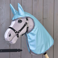 Sivý Hobby Horse od Hobby Horse LarDen s čiernou uzdečkou, veľkými plstenými očami a kapucňou Pláštenka Light Blue s ladiacimi ušami, zobrazený pred drevenou stenou.